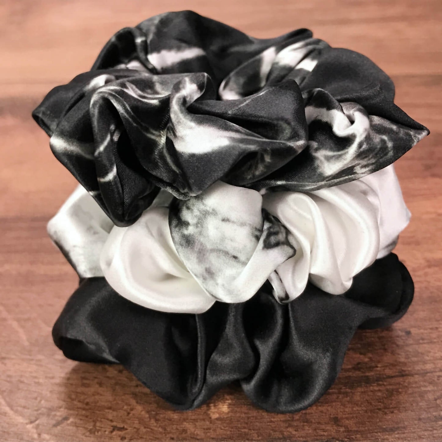 Large marble silk hair ties by Celestial Silk stacked on a wood vanit