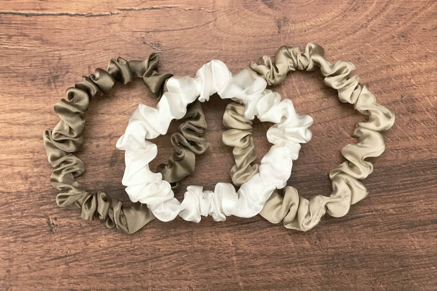 thin dark taupe ivory and taupe silk hair ties by Celestial Silk laying in a pile on a wood vanity