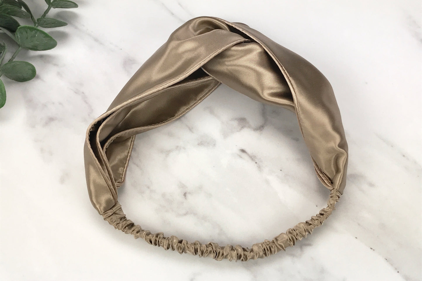 celestial silk twisted taupe silk headband for hair on counter with aloe