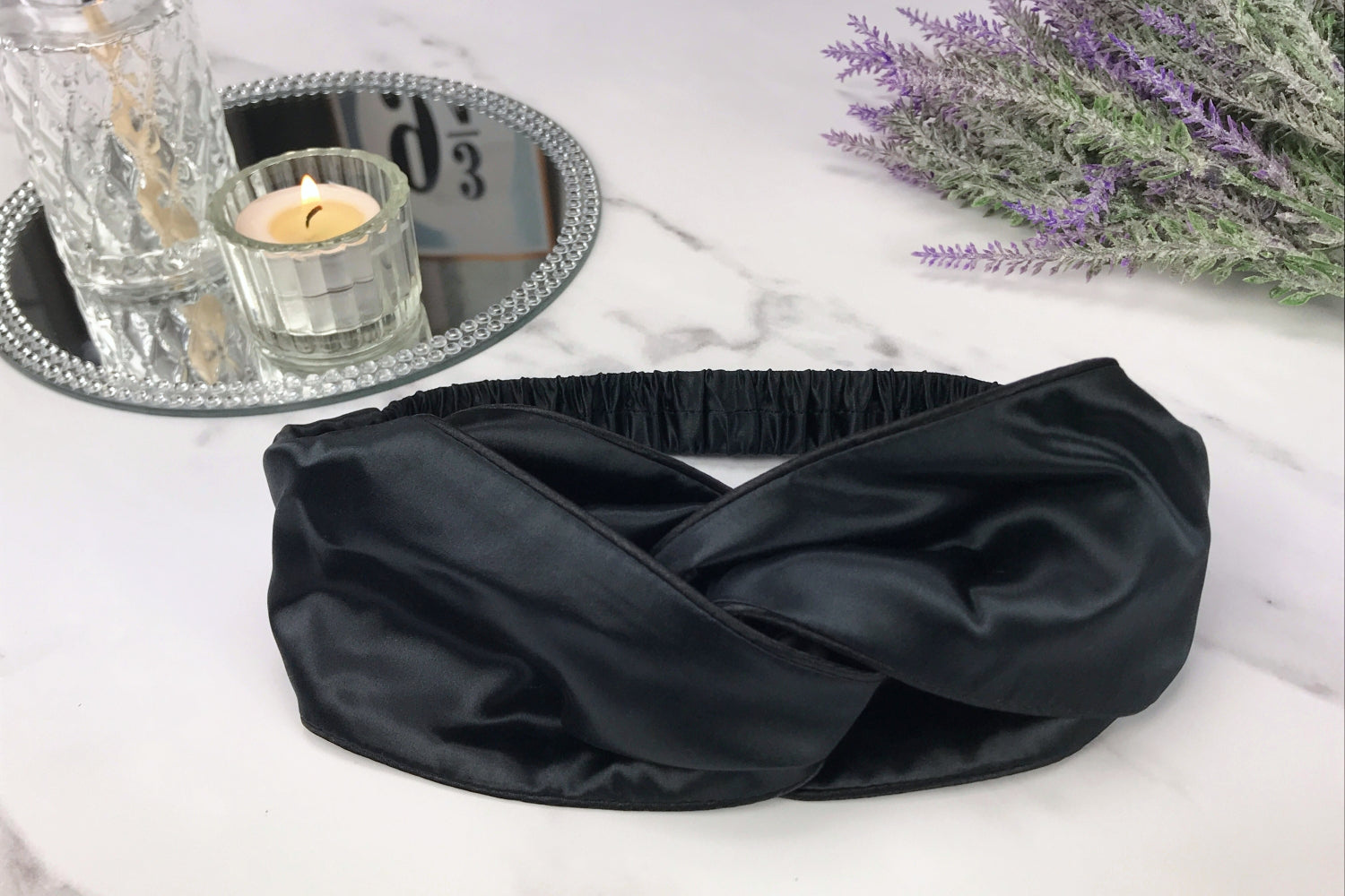 celestial silk twisted black silk headband for hair on counter with lavender and candle