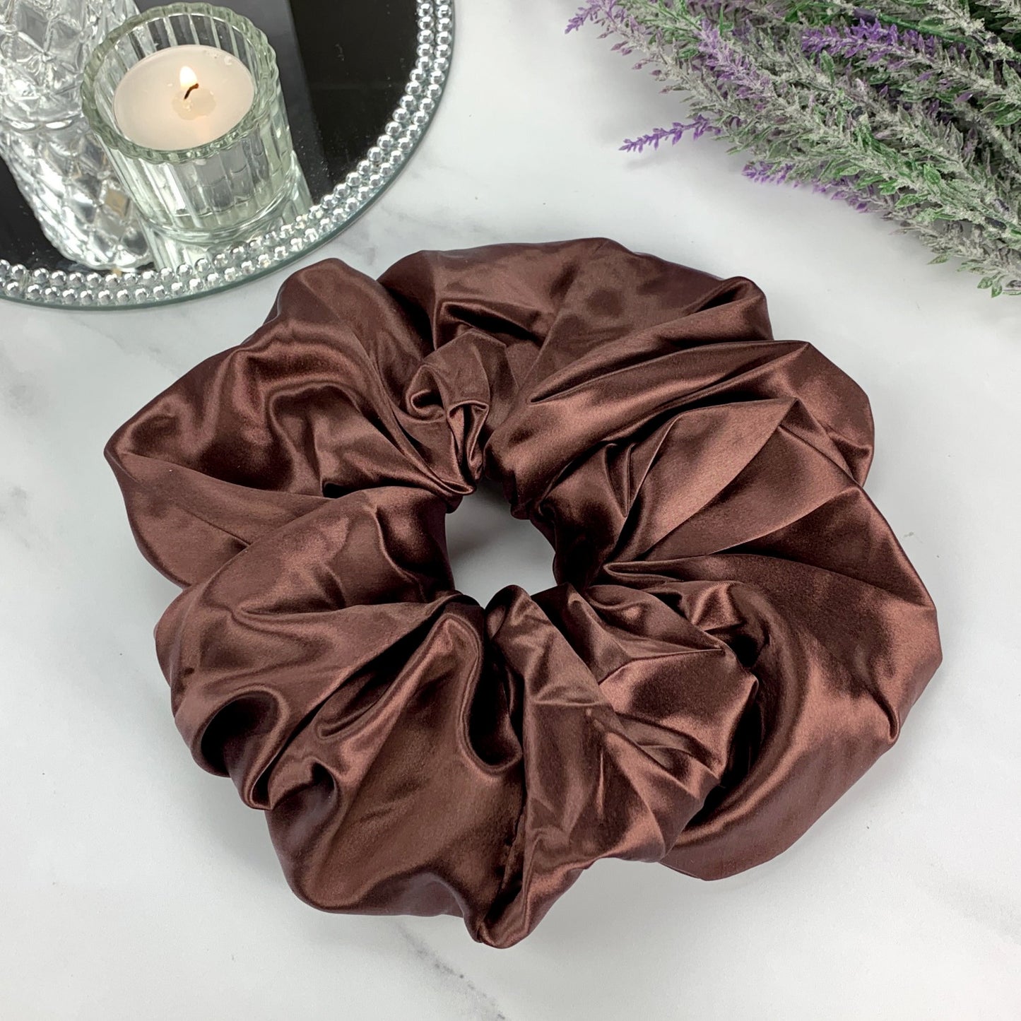 oversized chocolate silk scrunchie on marble counter with candle