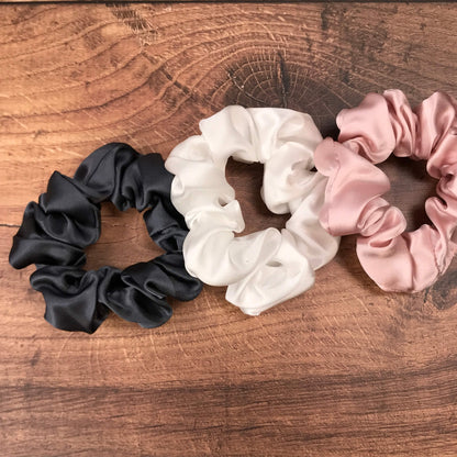 Large charcoal ivory and pink silk hair ties by Celestial Silk laying in a pile on a wood vanity
