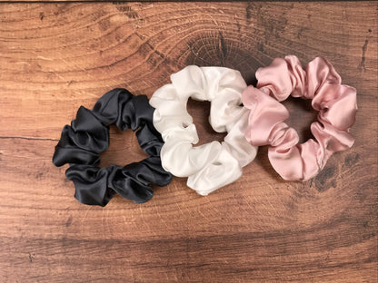 Large charcoal ivory and pink silk hair ties by Celestial Silk laying in a pile on a wood vanity