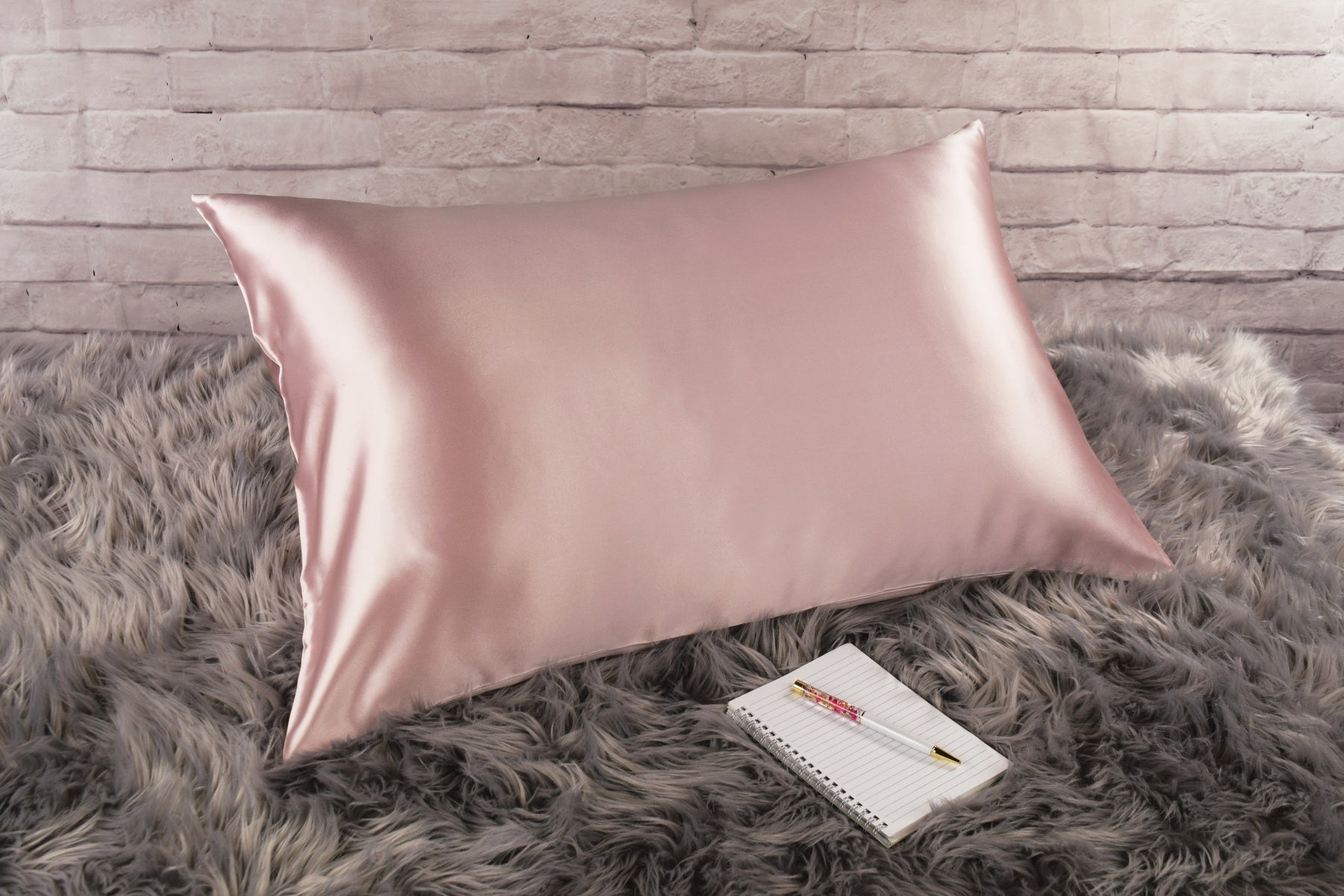 Celestial Silk 25 momme pink silk pillowcase on faux fur rug with notebook and pretty pen