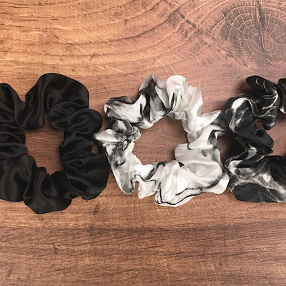 Large marble silk hair ties by Celestial Silk laying side by side on a wood vanity