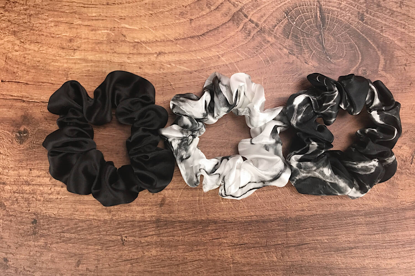 Large marble silk hair ties by Celestial Silk laying side by side on a wood vanity
