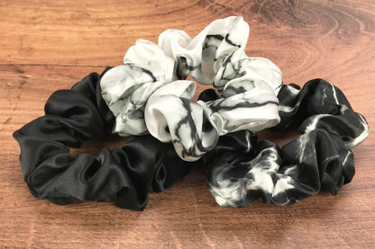 Large marble silk hair ties by Celestial Silk laying in a pile on a wood vanity