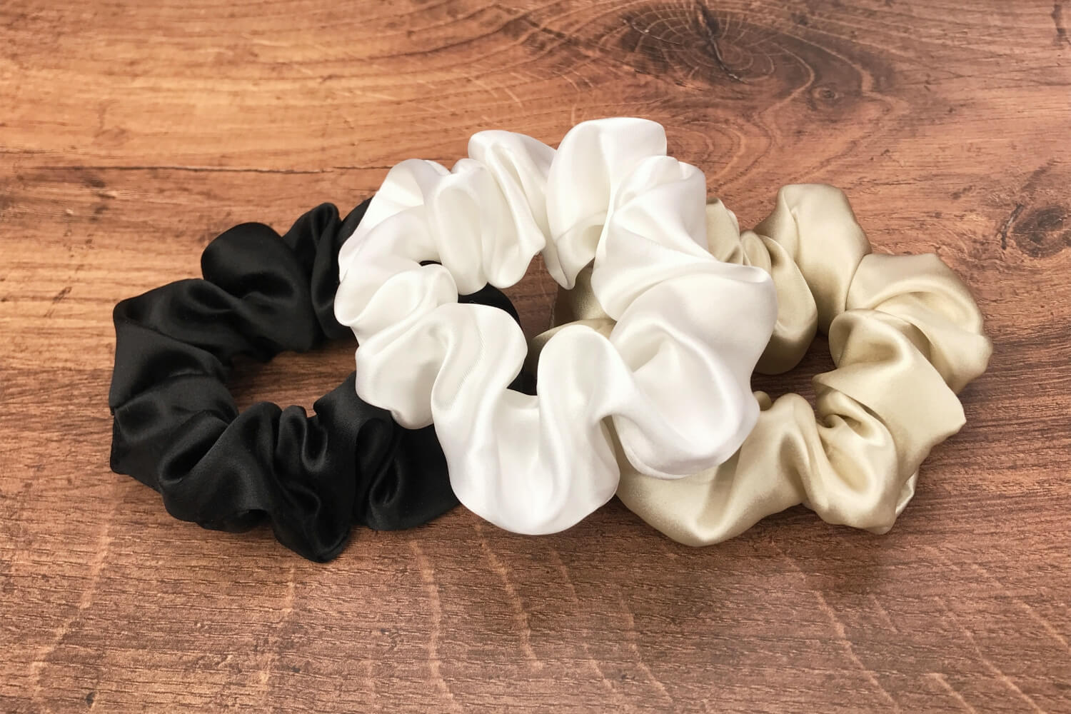 taupe ivory and black silk hair ties by Celestial Silk laying in a pile on a wood vanity