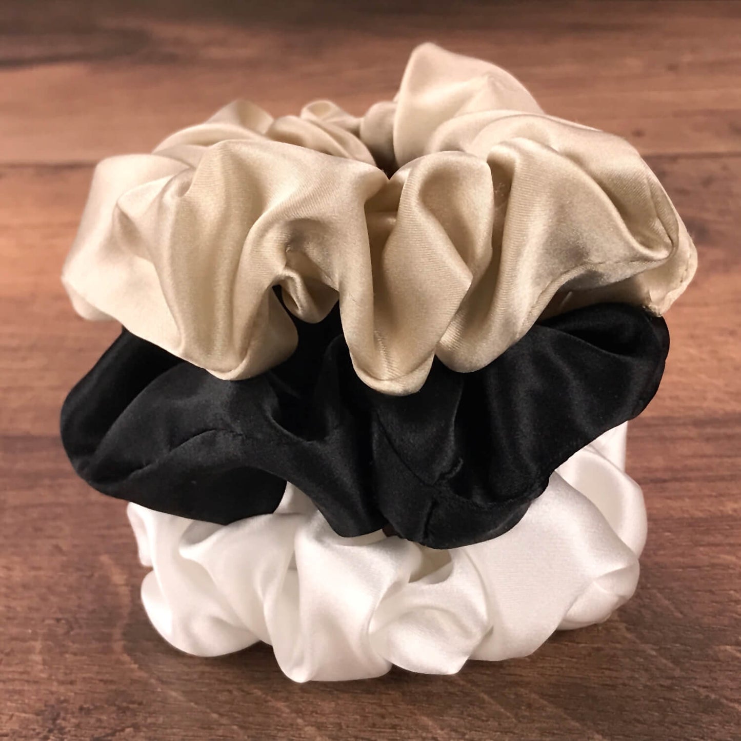 taupe ivory and black silk hair ties by Celestial Silk stacked in a pile on a wood vanity