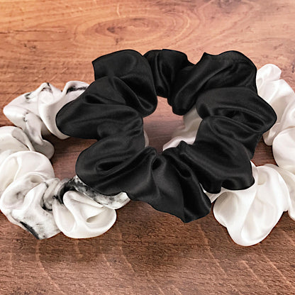 Large white marble, ivory and black silk hair ties by Celestial Silk laying in a pile on a wood vanity