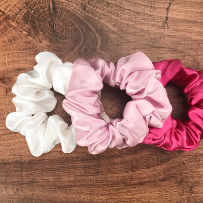 Large soft pink hot pink and white silk hair ties by Celestial Silk laying in a pile on a wood vanity