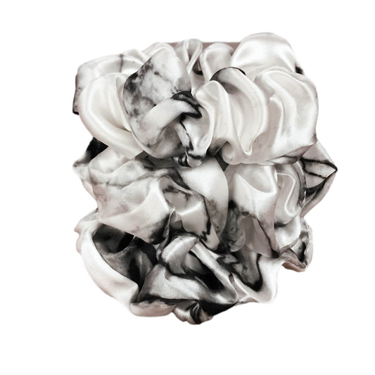 White marble silk scrunchies by celestial silk stacked with a white background