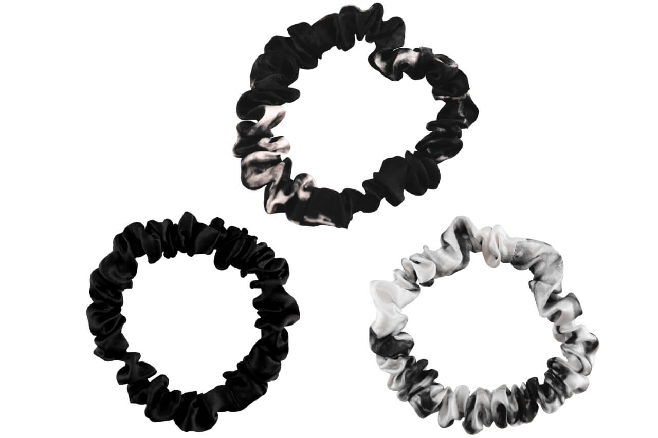 White marble black marble and black silk scrunchies by celestial silk stacked with a white background
