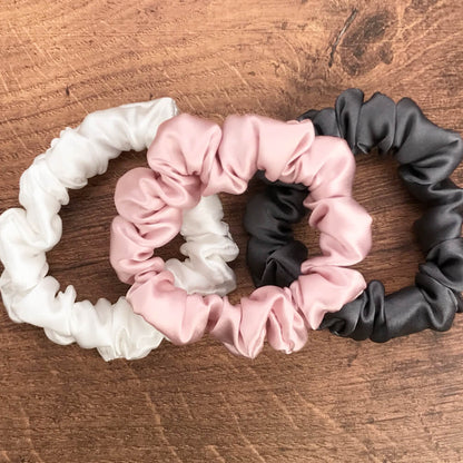 thin charcoal ivory and pink silk hair ties by Celestial Silk laying in a pile on a wood vanity
