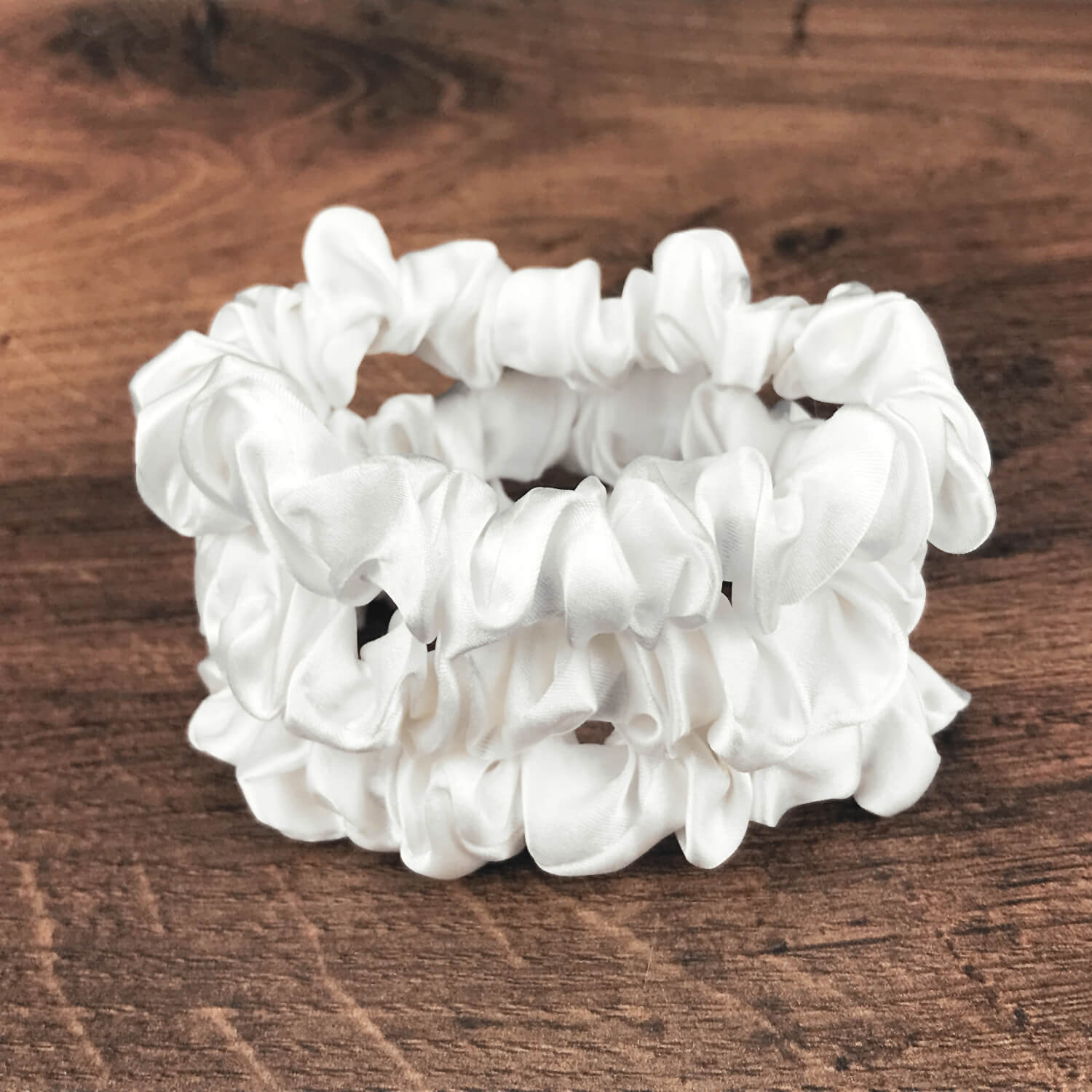 thin ivory silk hair ties by Celestial Silk stacked in a pile on a wood vanity