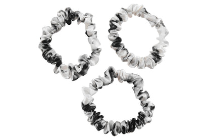White marble silk scrunchies by celestial silk stacked with a white background