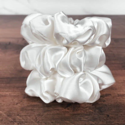 Large white silk hair ties by Celestial Silk stacked on a wood vanity